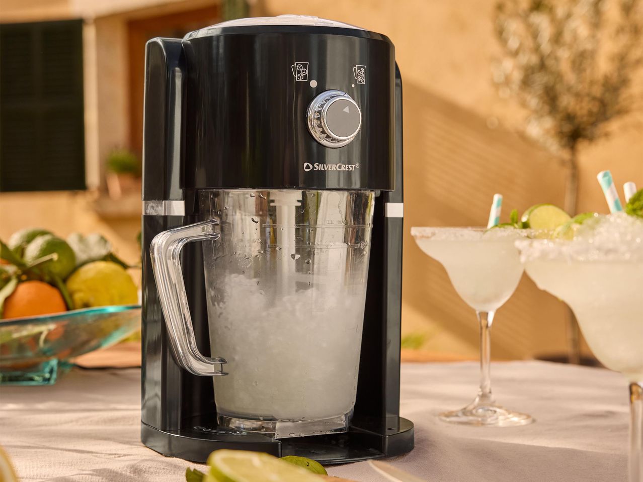 Egy fekete, retro stílusú koktélkészítő gép margaritákkal egy terasz asztalán.