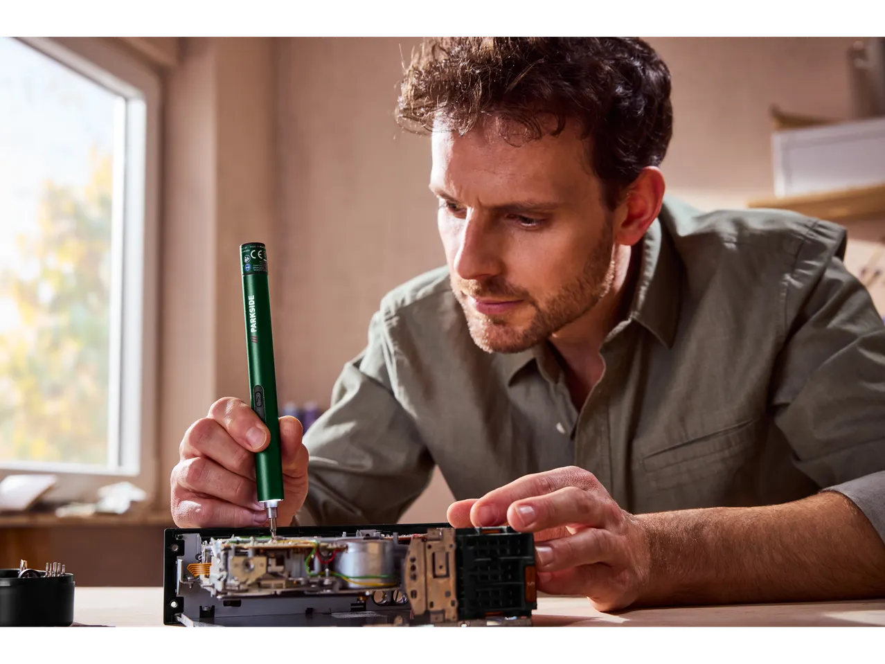 Vīrietis labo elektroniku ar mazu elektrisko skrūvgriezi.