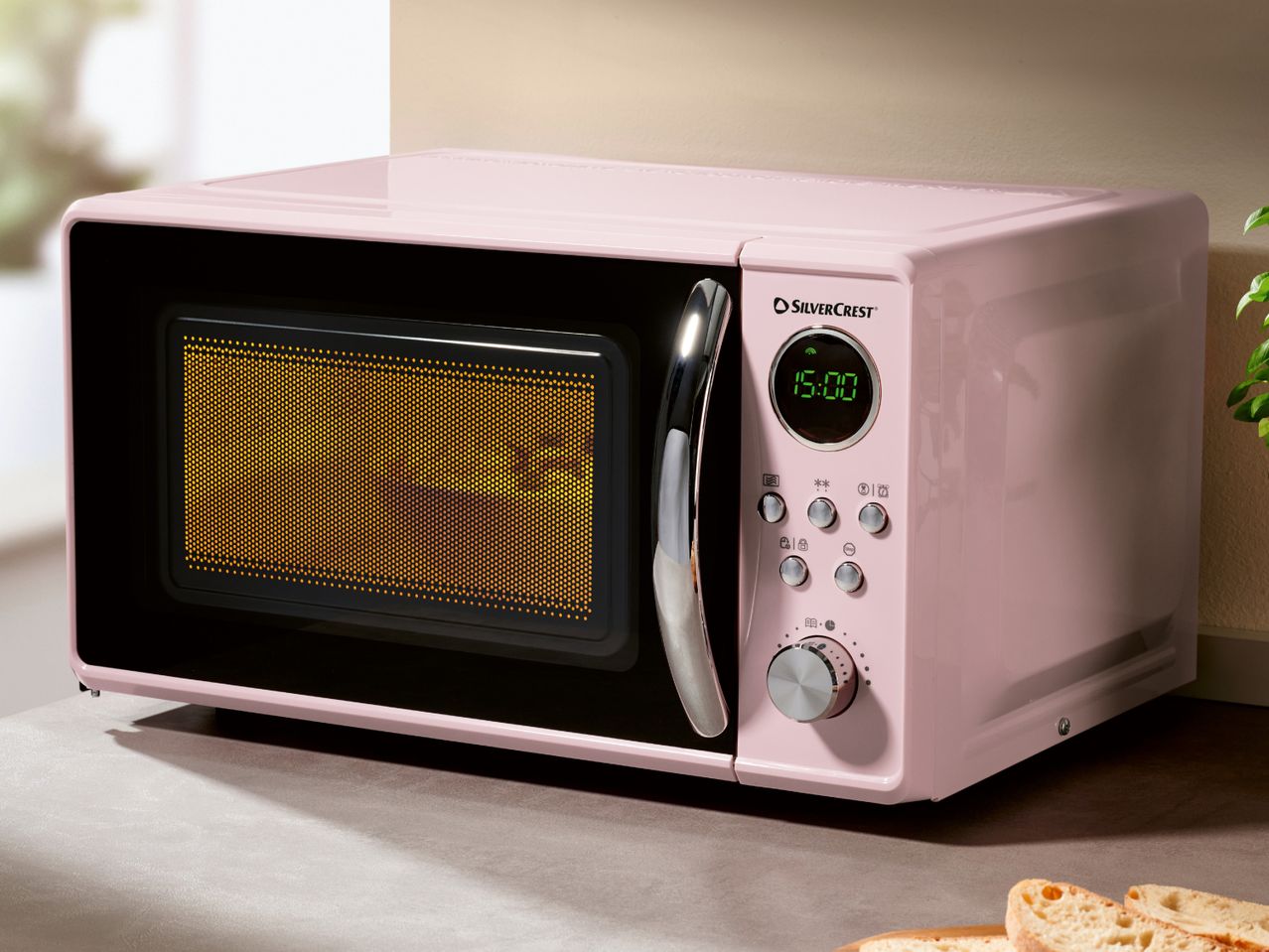 A pink SilverCrest microwave oven with a digital display showing 15:00.