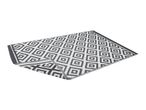 Grey and white geometric pattern outdoor rug, partially folded.