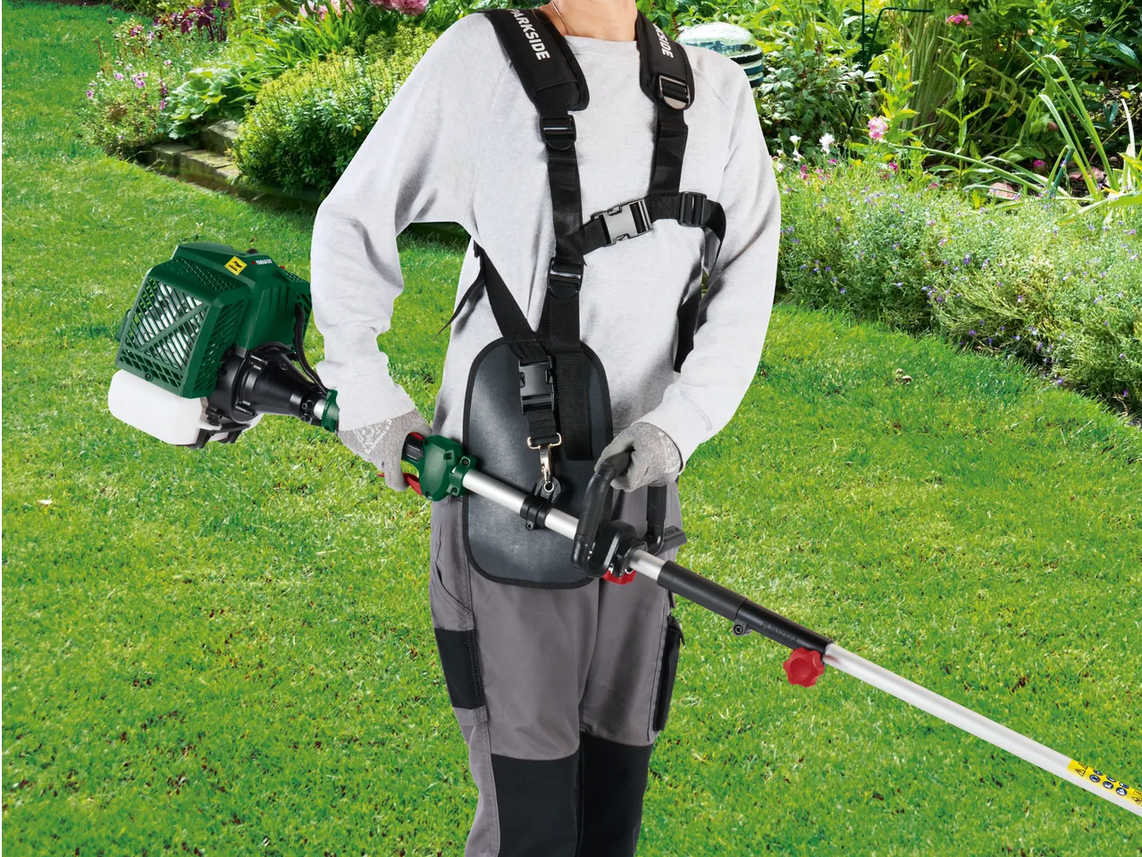 Person using a PARKSIDE® 4-in-1 Petrol Multi Tool with harness in a garden.
