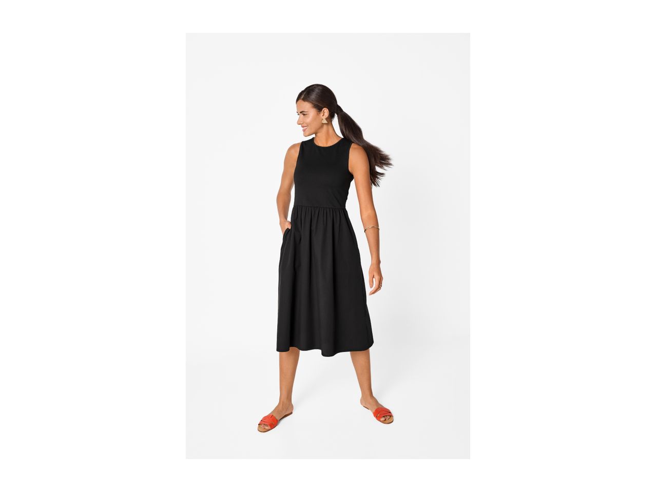 Woman in a black sleeveless midi dress with pockets, wearing orange flat sandals.