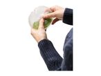 Hands holding a reusable breast pad with green liquid inside