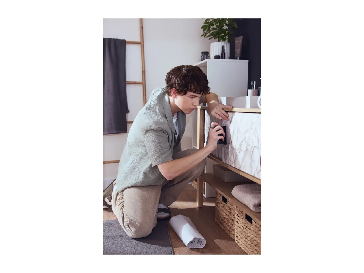 A man applying marble-effect self-adhesive film to a bathroom cabinet.