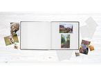 Álbum de fotos aberto com fotografias e cantos em uma mesa de madeira.
