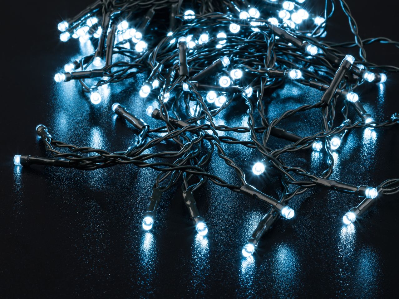 Close-up of bright blue LED string lights on a dark, reflective surface.