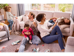 O familie fericită se joacă pe podeaua din sufrageria lor.