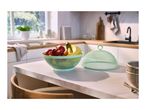 Fruit bowl with apples, grapes, and bananas, next to a mesh food cover in a kitchen.