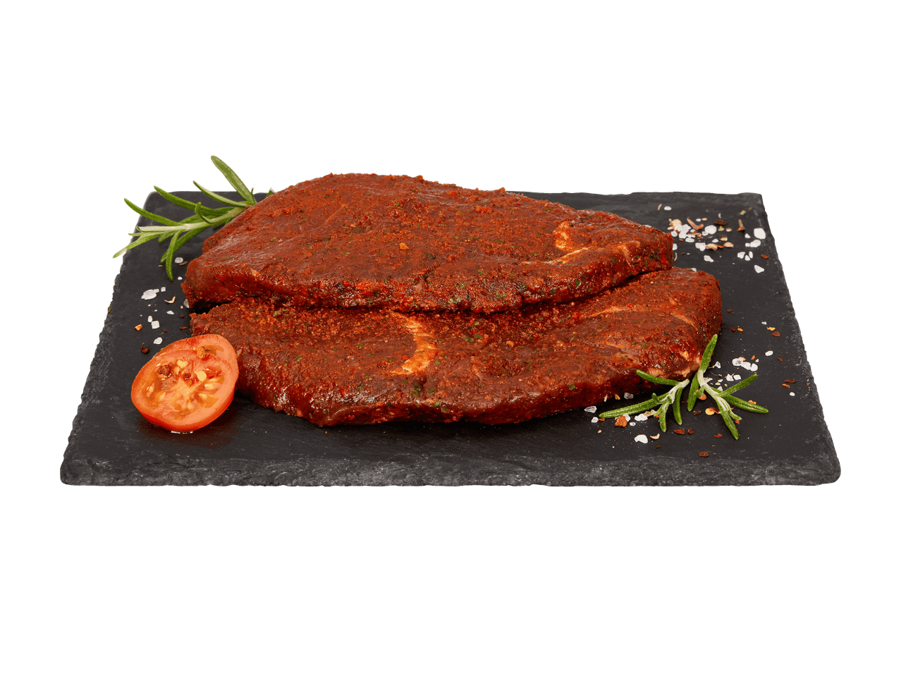 Zwei marinierte Steaks mit Rosmarin und Tomate auf einer Schieferplatte.