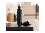 Black nose and ear hair trimmer on a dark surface with a blurred bathroom background.