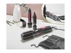 Hair styler with multiple brush attachments and a black storage bag on a table.