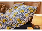 Close-up of a bed with lemon-printed bedding and a bedside lamp.