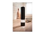 Black electric salt grinder on a wooden kitchen counter with a bowl and spoon.