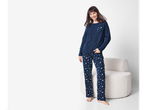 Smiling woman in Esmara® navy fleece pyjamas with white stars, standing next to a chair.