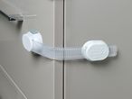 White child safety lock securing two light grey cabinet doors.