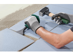 Homem a assentar azulejos com um cinzel manual PARKSIDE e um martelo.
