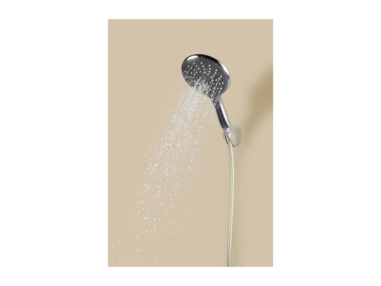 A chrome shower head spraying water against a light brown background.