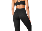 Mulher em leggings CRIVIT® pretas com padrão e sutiã desportivo preto