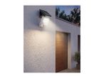 Solar-powered LED outdoor wall light with motion sensor illuminating a house entrance