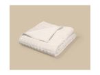 Folded beige quilted blanket on a light brown background