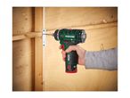 Hand holding a cordless drill, screwing a metal bracket into a wooden wall.