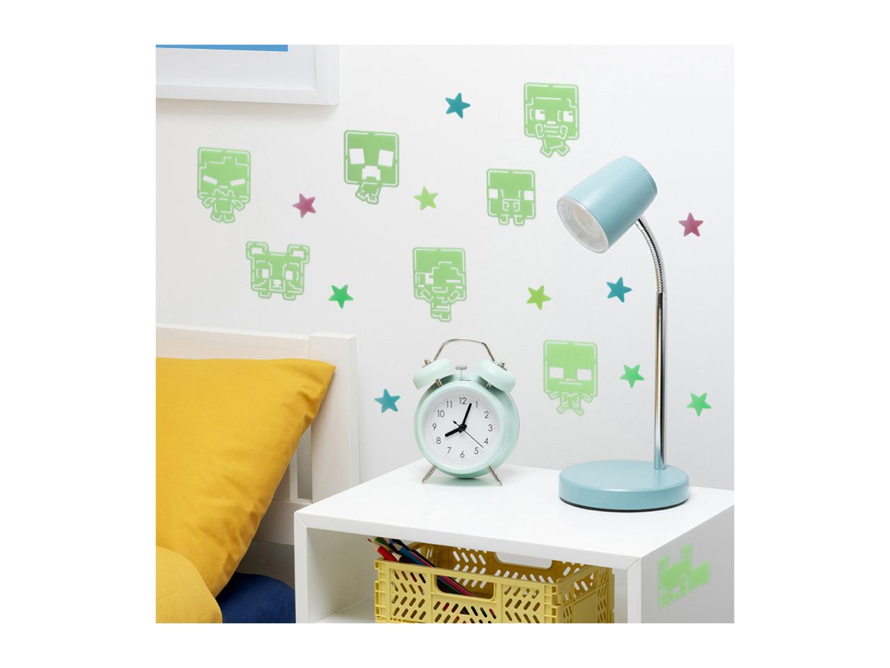 Minecraft-themed glow-in-the-dark wall decals adorn a child's bedroom, complementing a pastel-colored desk lamp and alarm clock.