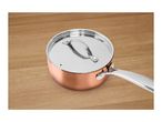 Copper-colored saucepan with a stainless steel lid on a wooden surface