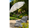 Guarda-sol LIVARNO branco num pátio com espreguiçadeira cinzenta e jardim florido.