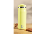Yellow travel mug with a silver band and logo, next to chocolate chip cookies.
