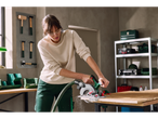 Woman using a Parkside® 20V Cordless Circular Saw to cut wood in a workshop.