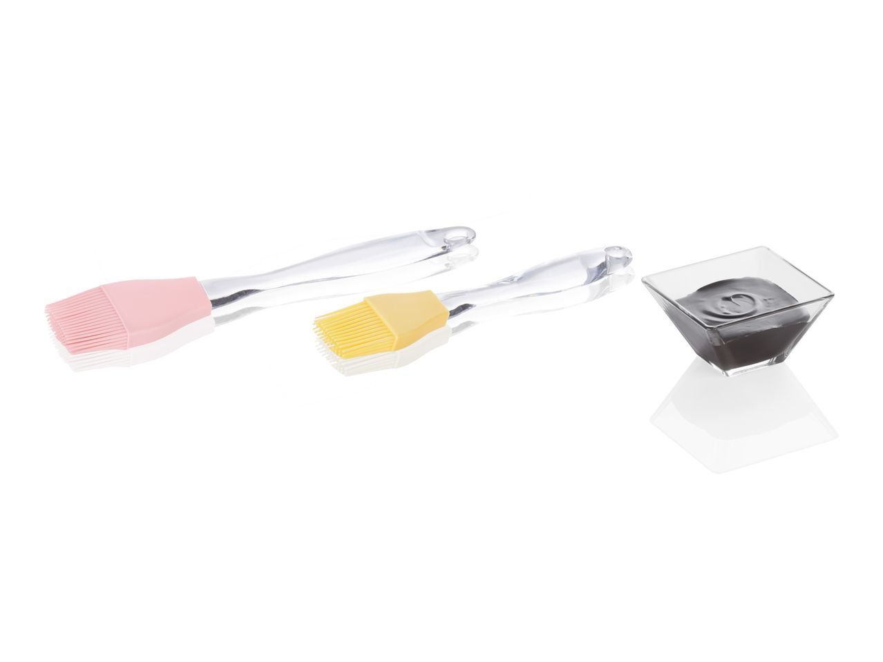 Two silicone pastry brushes and a small container of dark gray substance.