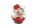 White orchid in a glass vase with red decorative stones and a red heart.