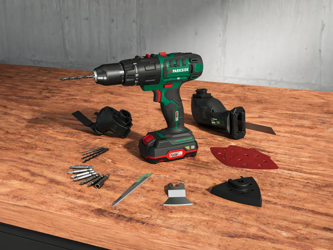 Parkside X20V Team cordless drill, reciprocating saw, and accessories on a wooden table.
