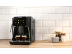 Automatic coffee machine with two espresso cups, coffee beans, and sugar on a wooden counter.