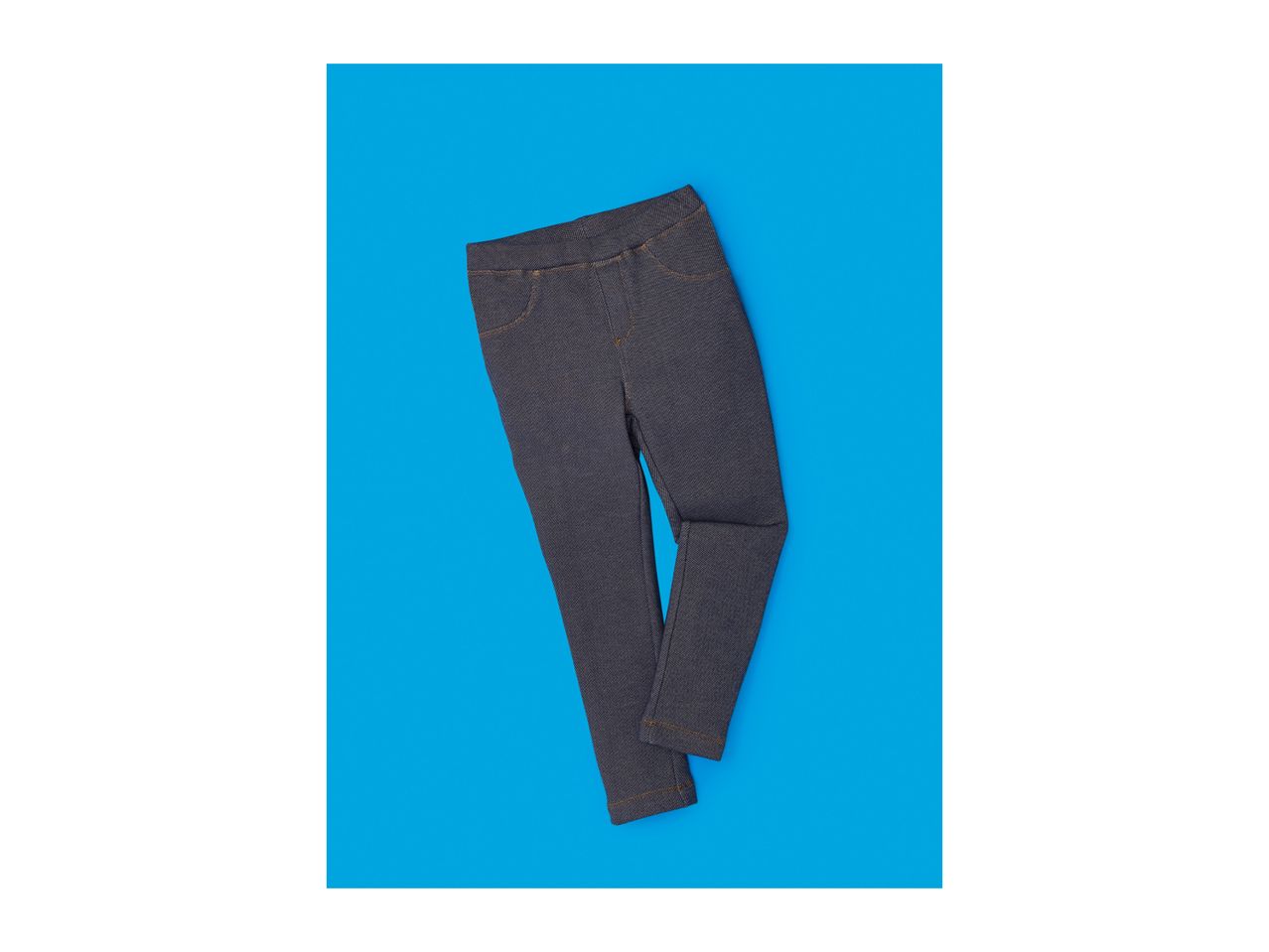 Dark blue denim jeggings with orange stitching on a blue background
