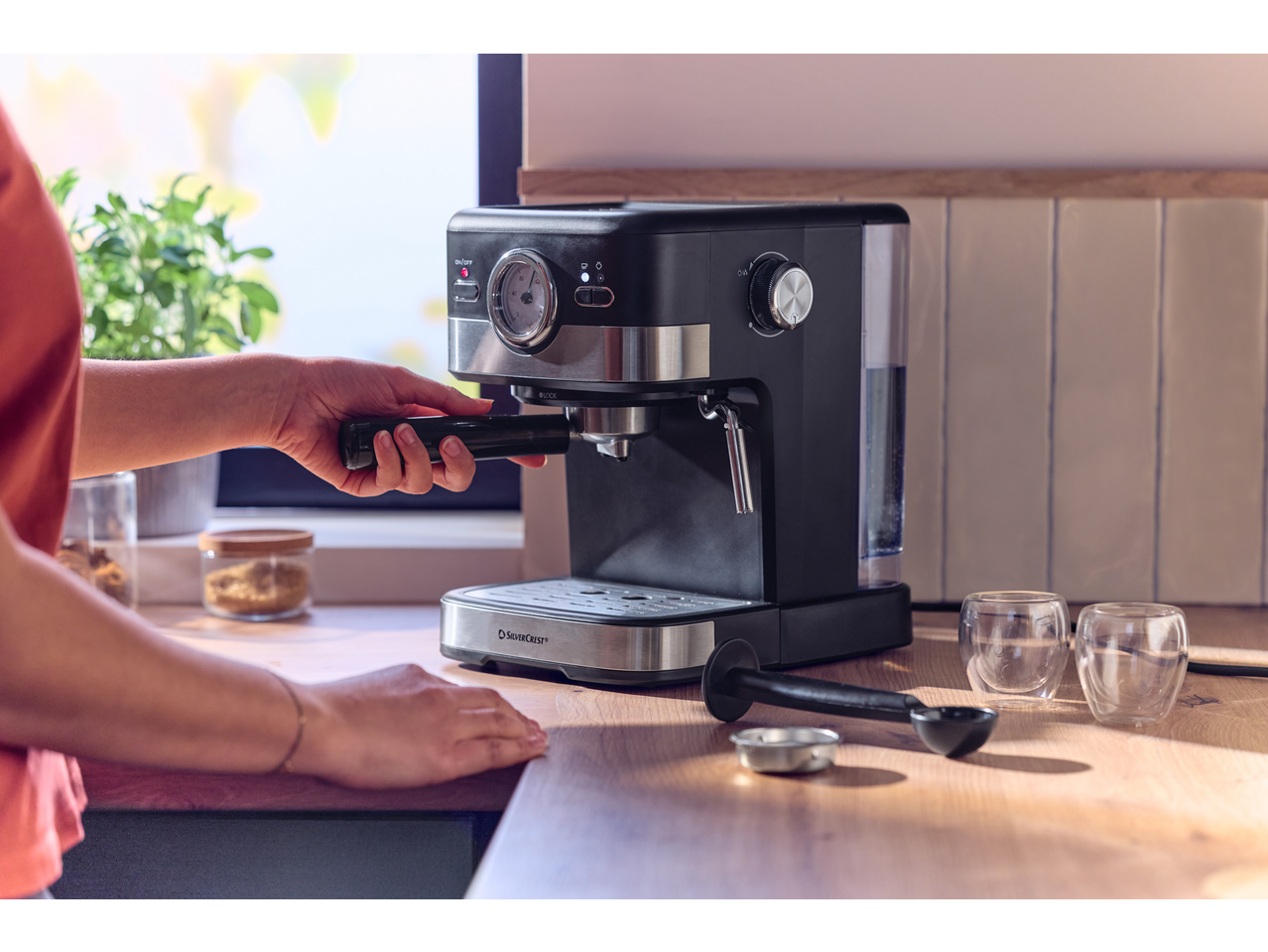 Espressor negru și argintiu cu o persoană care introduce portafiltrul.