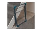 Foldable clothes drying rack standing next to a carpeted staircase and wooden floor.