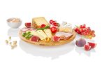 A round bamboo cheese board displays various cheeses, figs, and grapes.