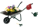 Carrinho de mão com flores, ferramentas de jardim, luvas e regador.