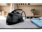 Gerador de vapor preto e camisa azul dobrada numa tábua de engomar.