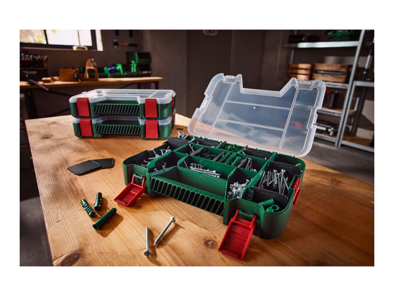 Open and closed organizer boxes with screws and wall plugs on a wooden workbench.