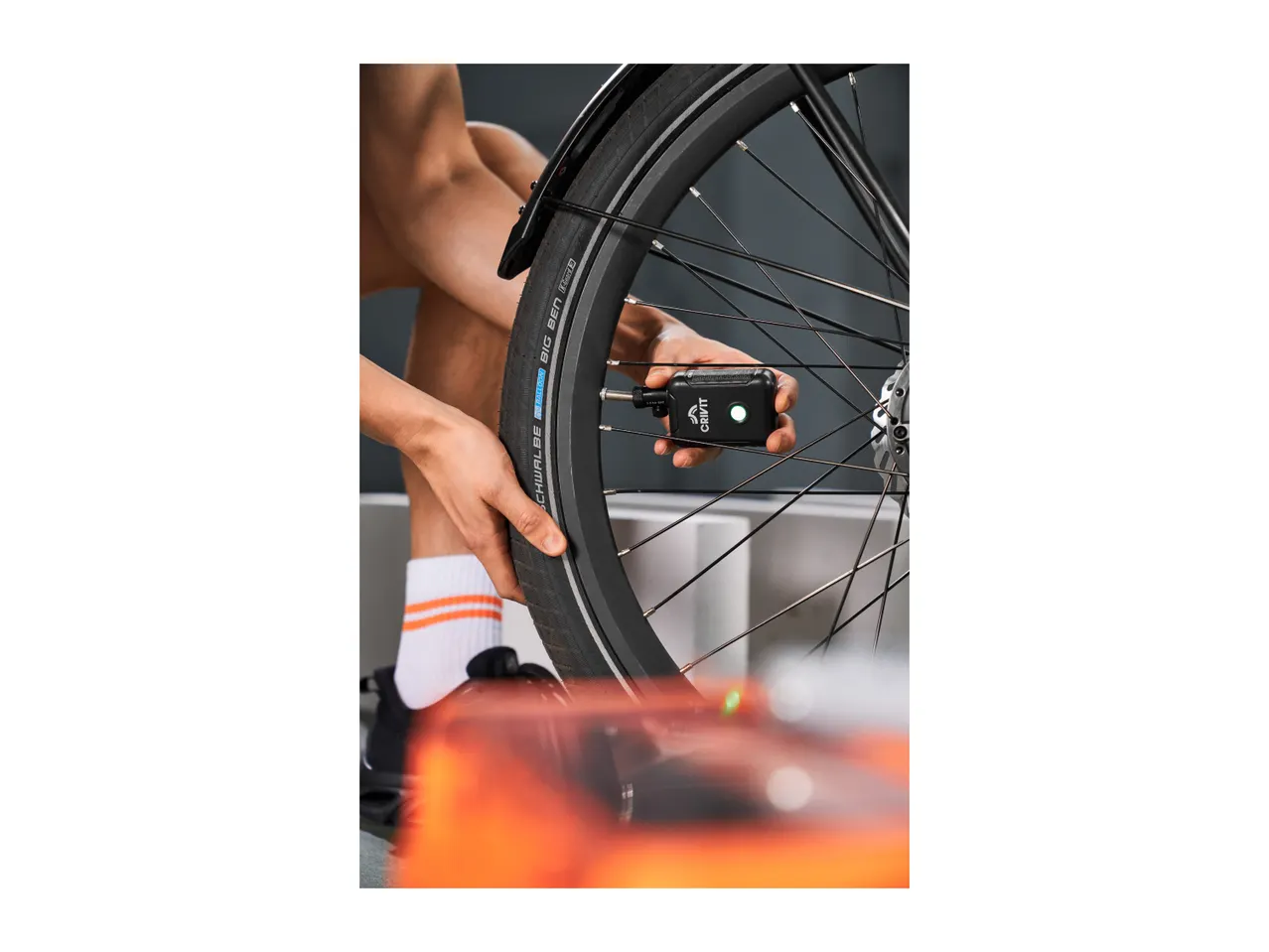 Person checking bicycle tire pressure with a digital gauge.
