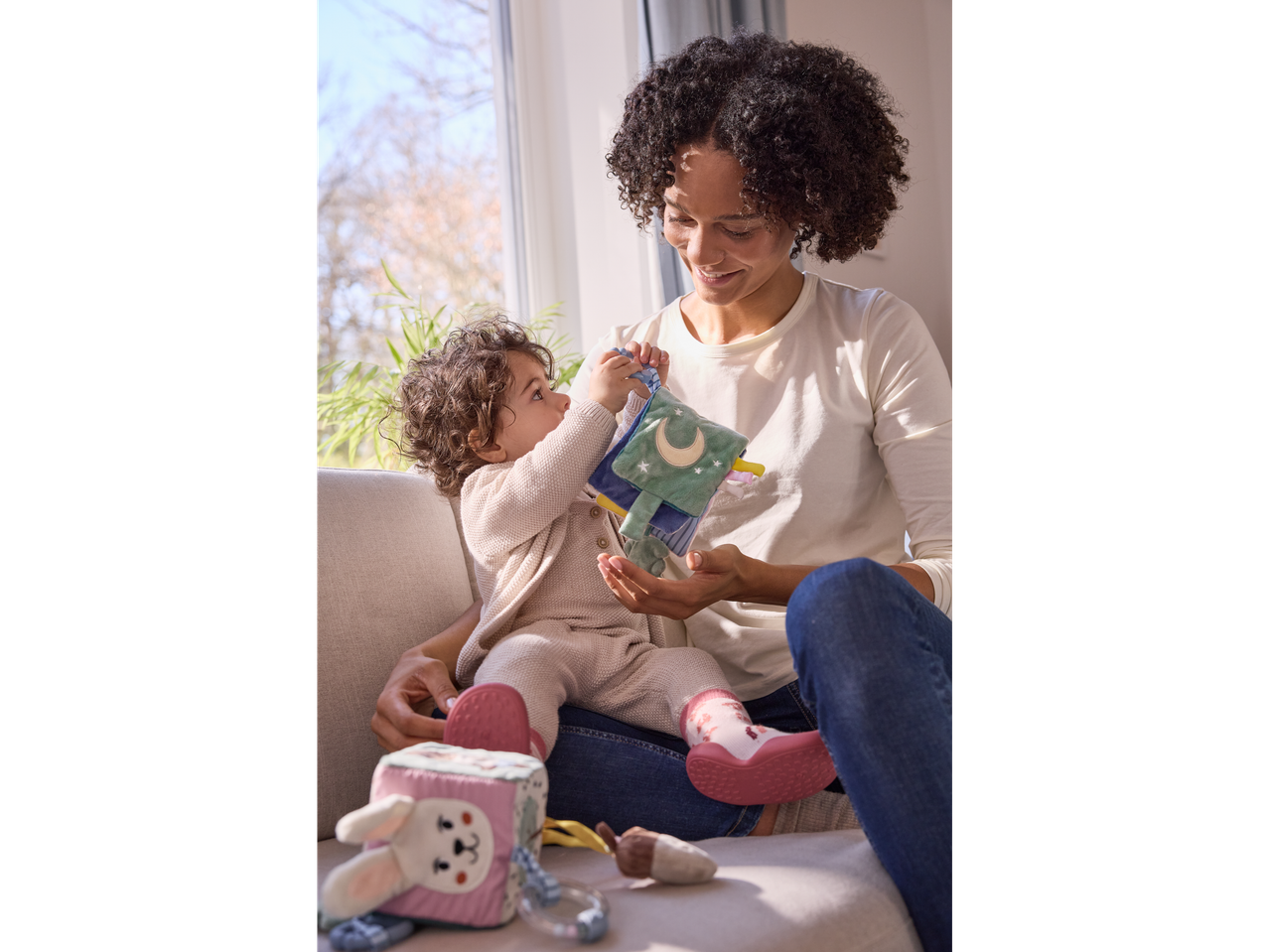 Mother and baby playing with soft toys.