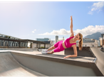 Woman in pink workout clothes doing a plank outside.