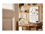 Home office with a whiteboard calendar, desk, and shelves with plants.