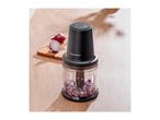Food chopper with diced red onions on a wooden table, with a cutting board and whole onions in the background.
