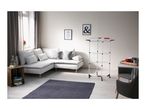 Living room with white corner sofa, dark blue rug, and a white clothes drying rack.