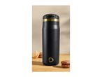 Black travel mug with a gold band and logo, next to two macarons on a wooden surface.