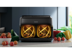 Philips Air Fryer with dual basket and illuminated interior, surrounded by fresh vegetables.