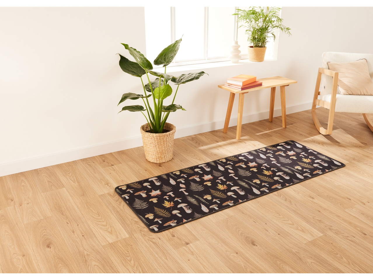 A black mushroom-patterned runner rug on a light wood floor in a bright room.